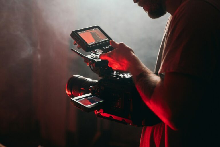 man in white t-shirt holding black video camera